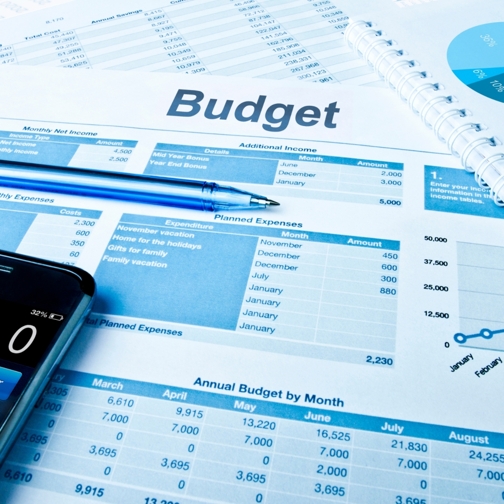 A financial budget spreadsheet with charts, figures, and a blue pen placed on the document, representing business budgeting, financial planning, and expense management.