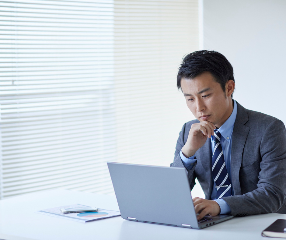 Business professional analysing information on a laptop in a modern office environment, representing strategic decision-making, executive insight, data-driven analysis, and focused leadership in enterprise and technology-driven organisations.